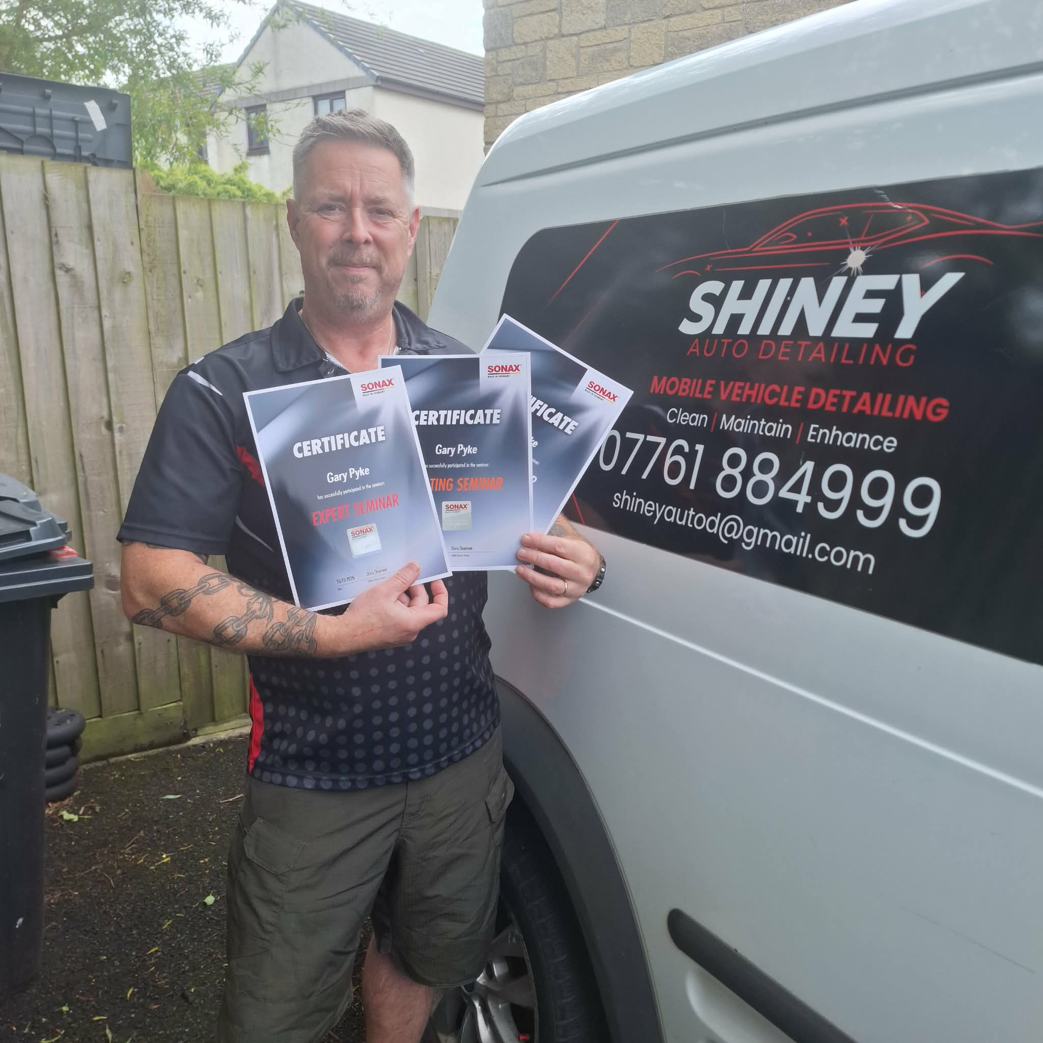 Gary, Shiney Auto Detailing owner, holding three SONAX detailer certificates beside his Shiney-branded van